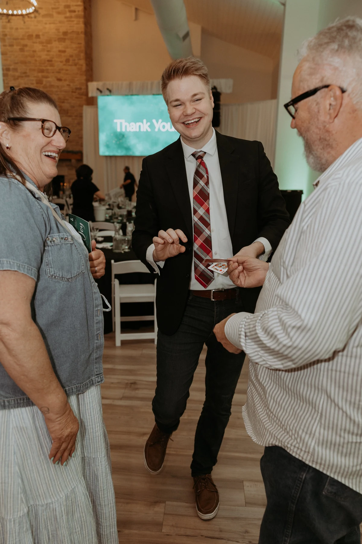 Chris Marvell sharing a laugh during a card trick with two guests at Night of Joy