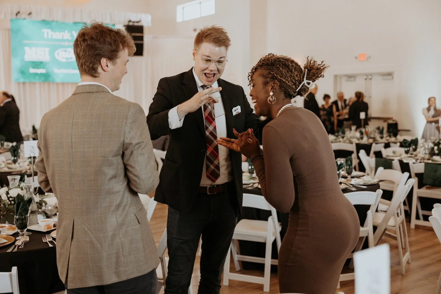 Chris Marvell laughing with two guests while performing at a corporate event